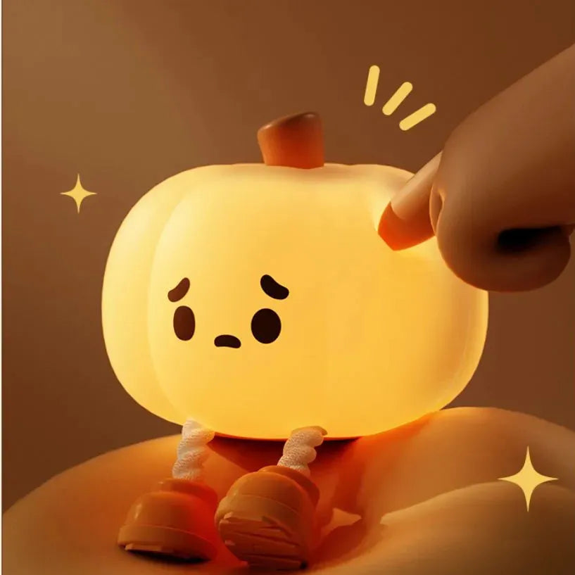 Pumpkin-shaped silicone night light with soft orange glow on wooden bedside table