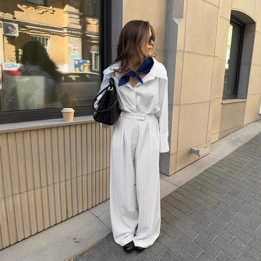 White striped loose-fit wide-leg trousers with a front zipper closure on a model.