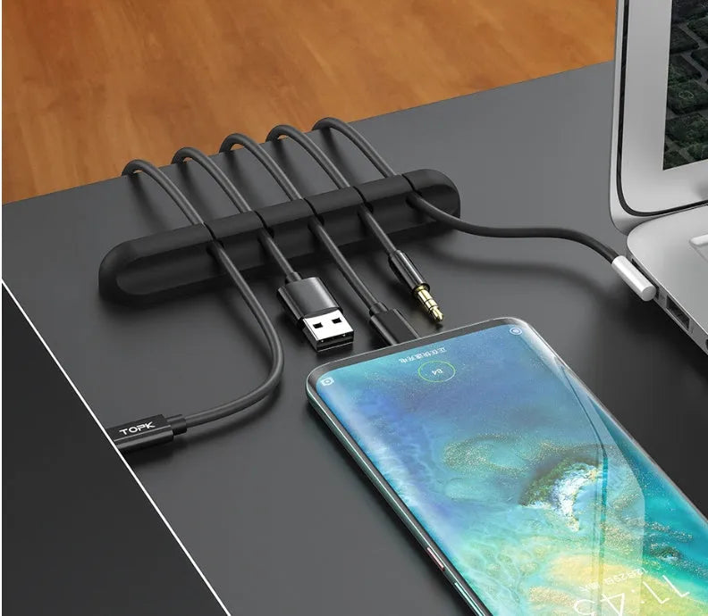 Black organic silicone desktop cable manager clips holding USB cables on a desk