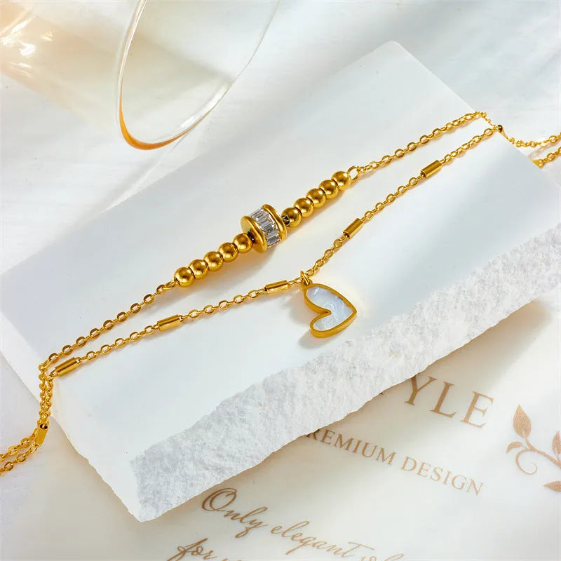 Gold titanium steel double-layer ankle chain with love heart charm and tassel on a white background