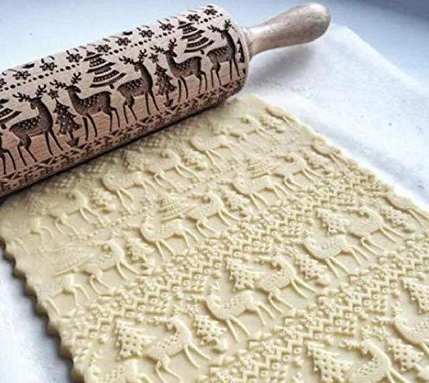 Wooden rolling pin with embossed Christmas patterns, 45cm long, on a kitchen worktop.
