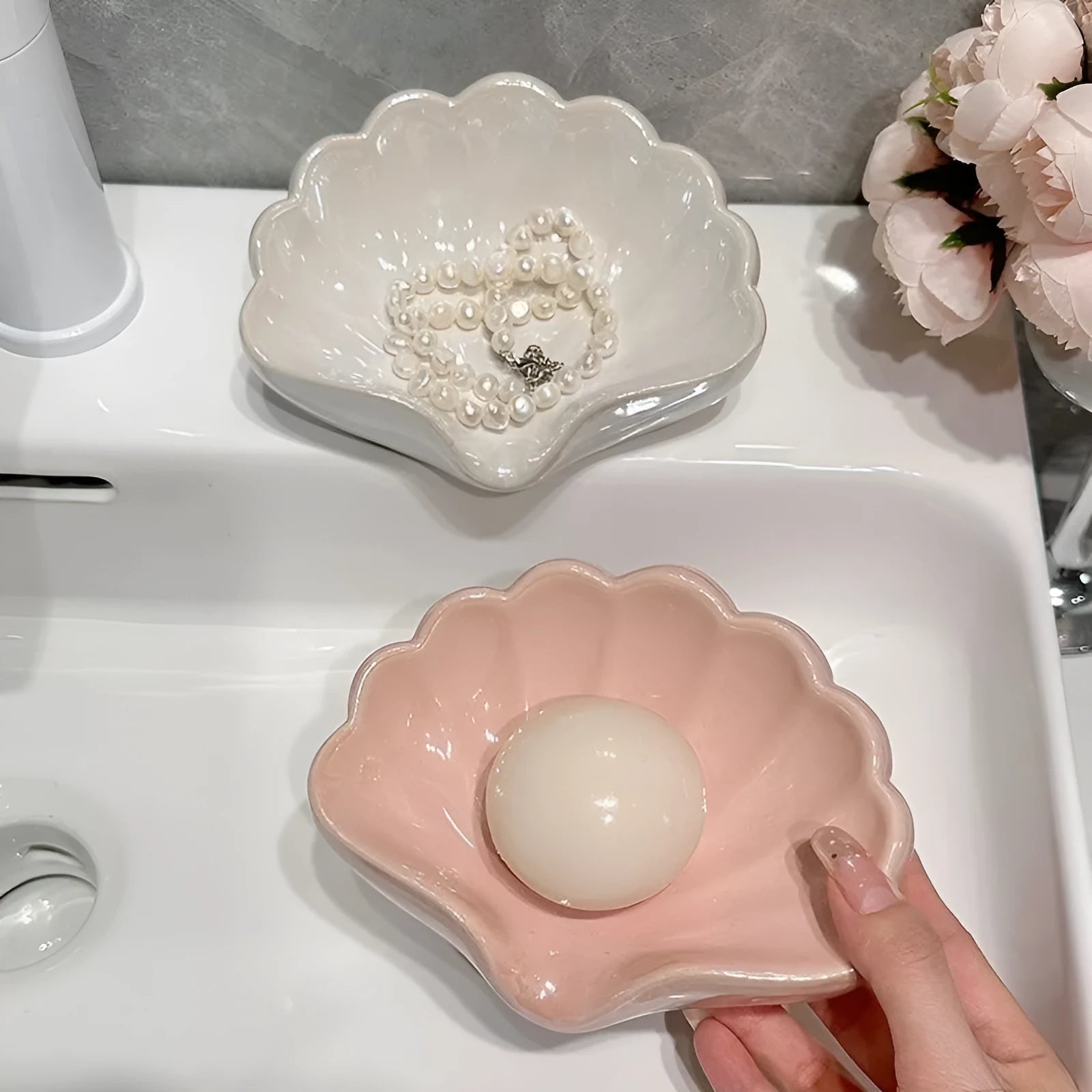 White shell-shaped plastic soap dish with drainage holes on a bathroom surface