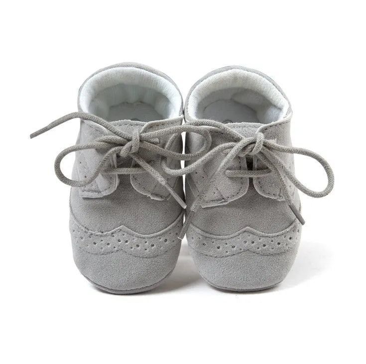 Vintage-style soft-soled baby shoes in synthetic leather, shown in light brown.