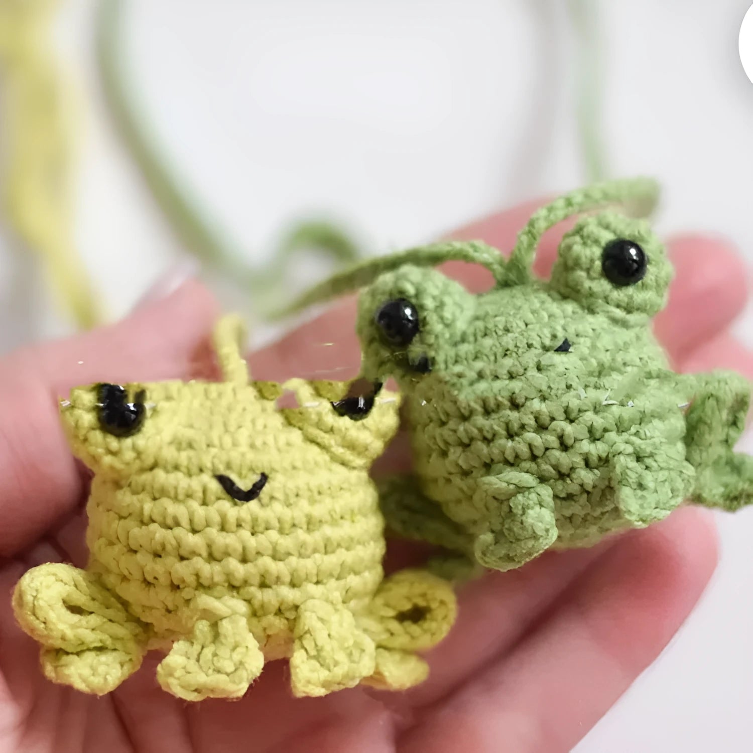 Handmade woven plush frog car pendant in green hanging from rear-view mirror