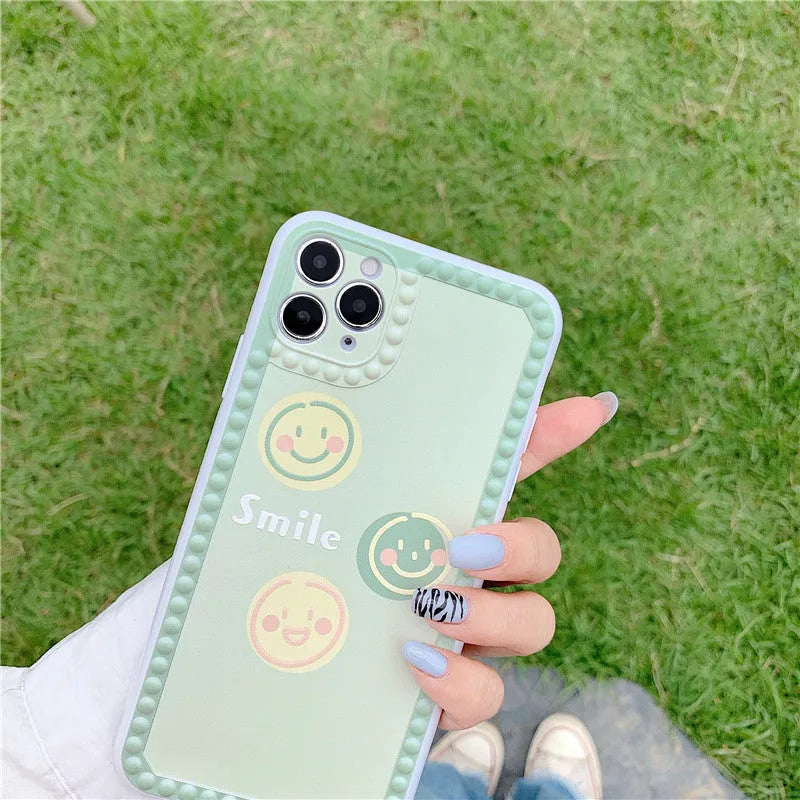 Green soft TPU iPhone case with geometric smiley face and polka dot frame design.