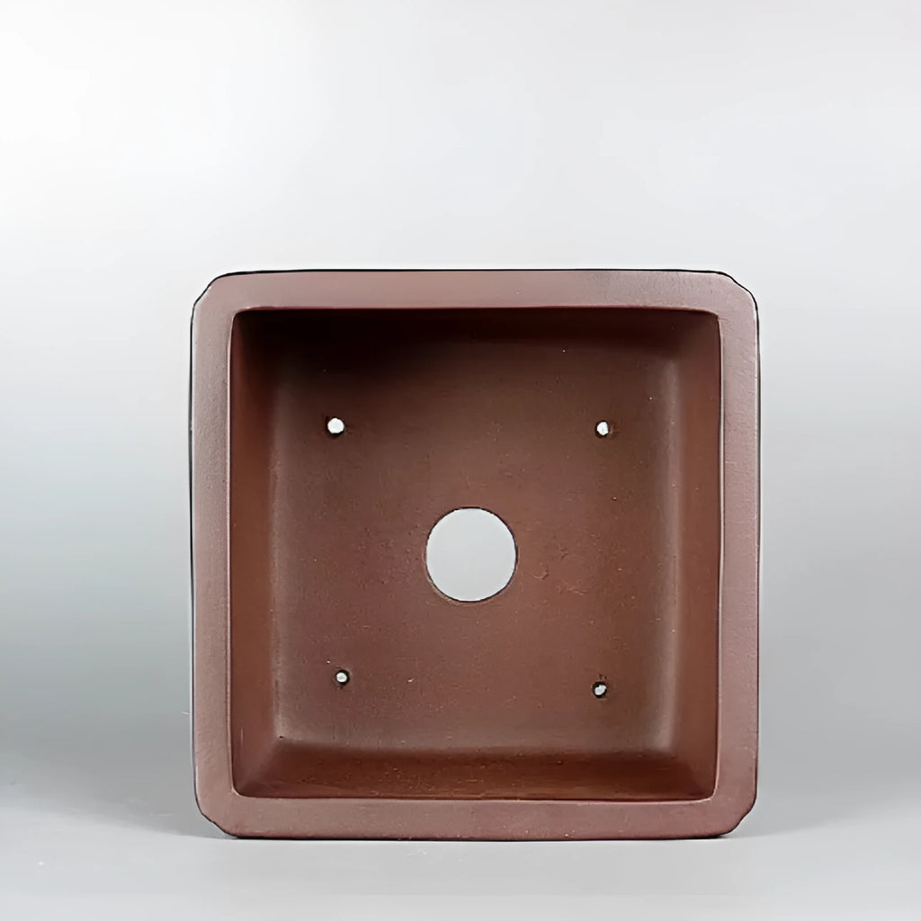Handmade brown antique classical purple clay ceramic flower pot on a windowsill.