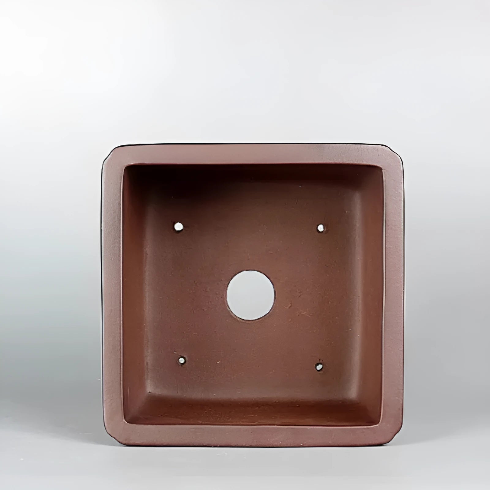 Handmade brown antique classical purple clay ceramic flower pot on a windowsill.