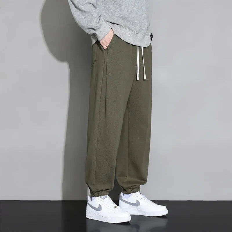 Men's loose grey cotton blend sports trousers with drawstring waist on a hanger.