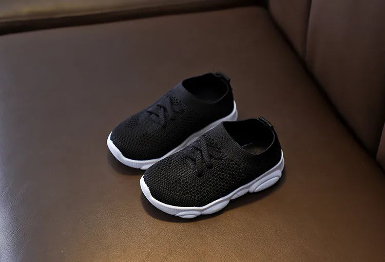 Children's white fabric lazy shoe with a non-slip rubber sole, shown on a foot.