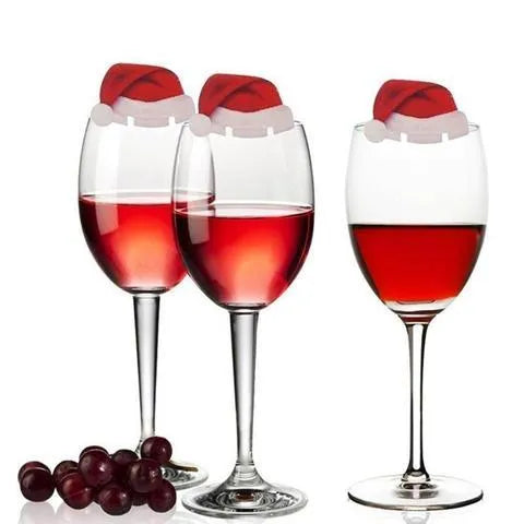 Set of 10 red non-woven fabric Santa hat decorations for wine glasses on a party table