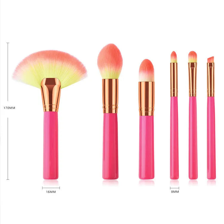 Pink cosmetic makeup brush set with wooden handles and synthetic bristles laid out on a surface