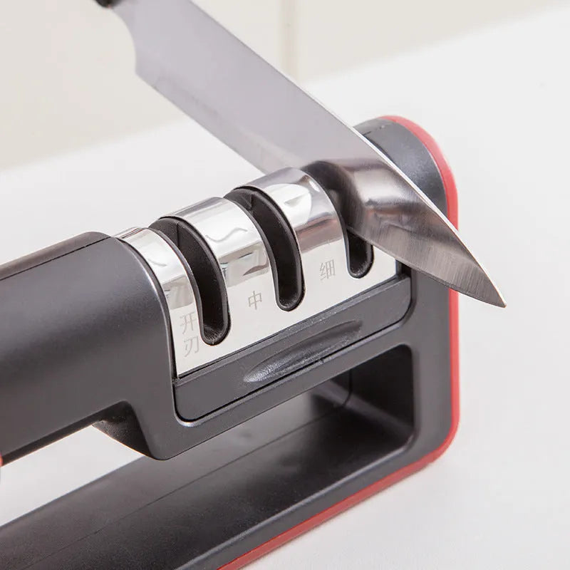 Black and red three-stage manual knife sharpener with rubber feet on base