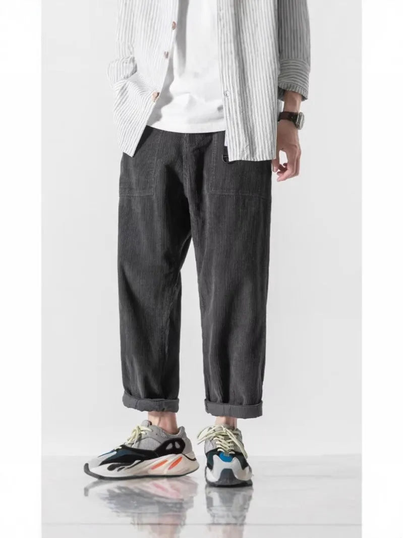 Man wearing loose straight leg tapered trousers in dark grey, showing relaxed fit and straight leg opening.