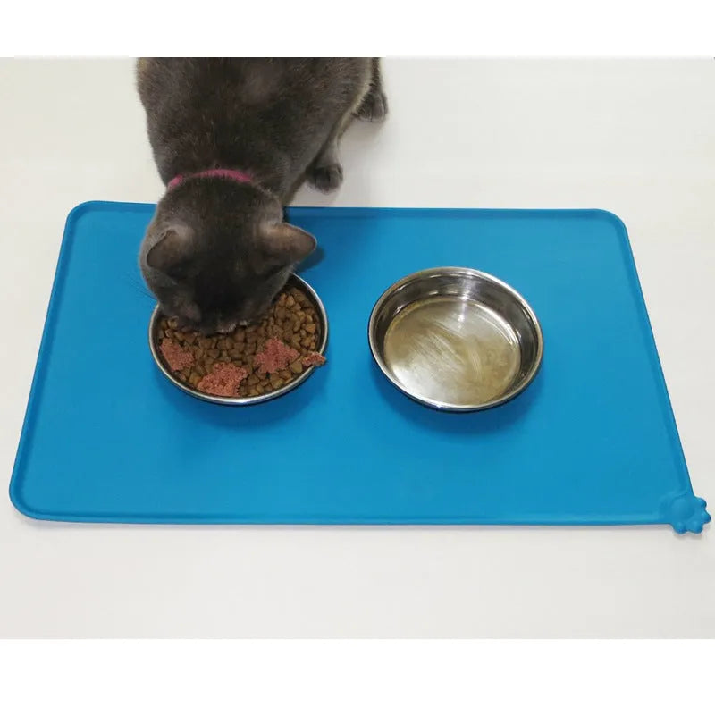 Black silicone dog food mat measuring 47 by 30 centimetres with non-slip surface and raised edges.