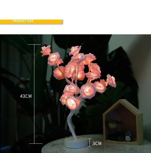 White and red rose flower LED table lamp with bonsai tree and garland lights on a table.