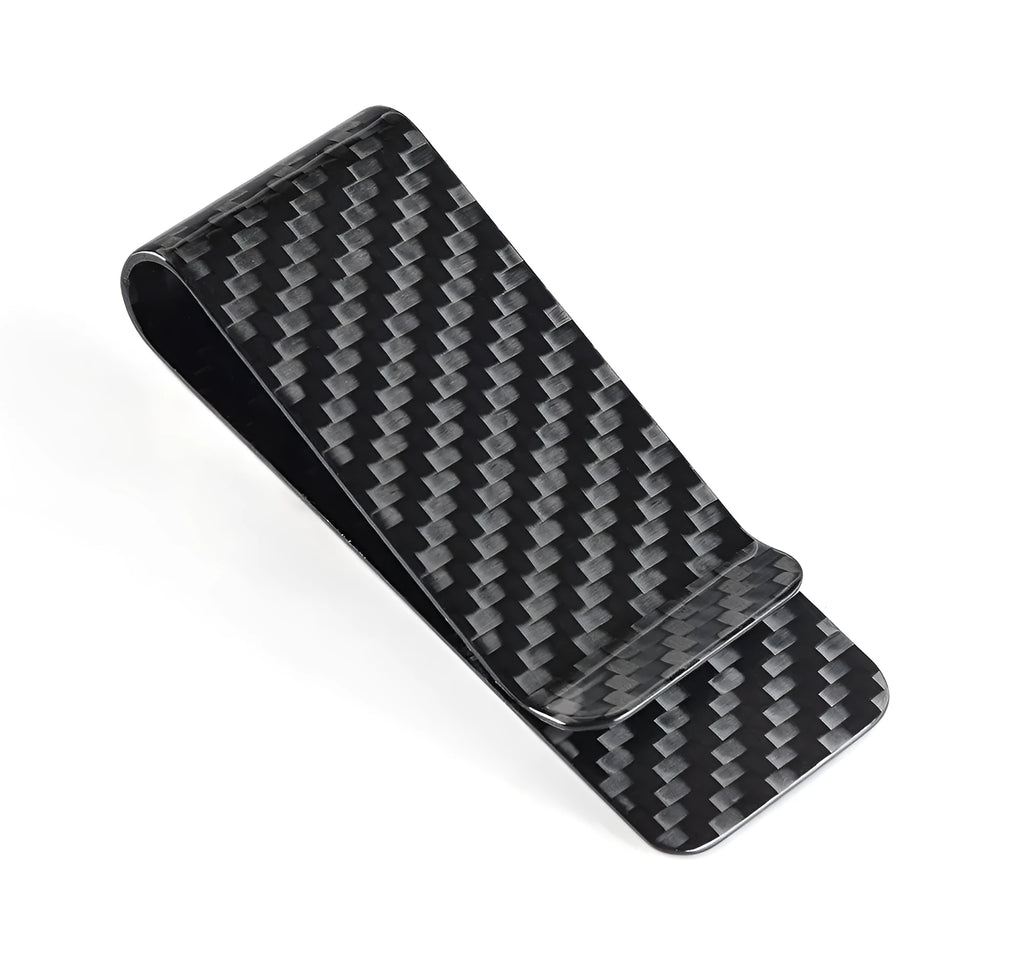 Black glossy striped carbon fibre money clip on a flat surface showing its slim profile and textured pattern