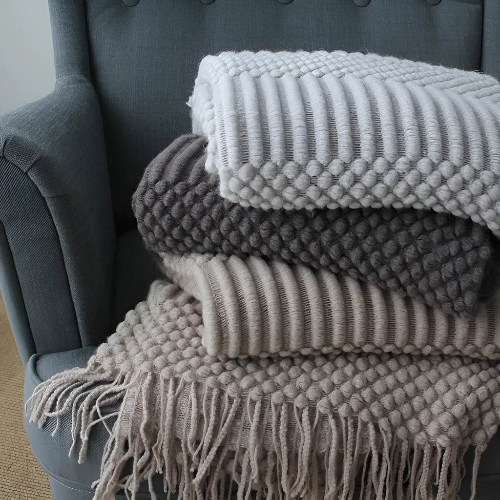 Small grey polyester nap blanket folded, showing its 127x170 cm size on a sofa.