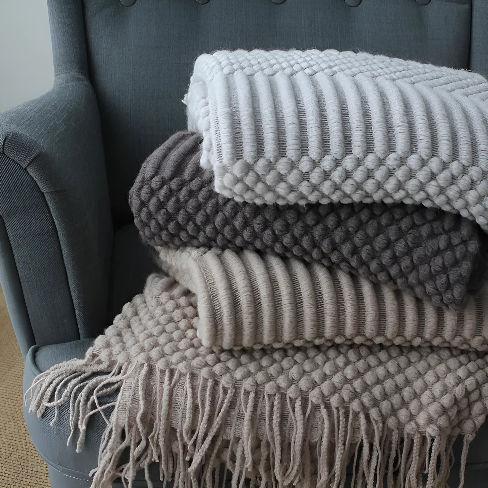 Small grey polyester nap blanket folded, showing its 127x170 cm size on a sofa.