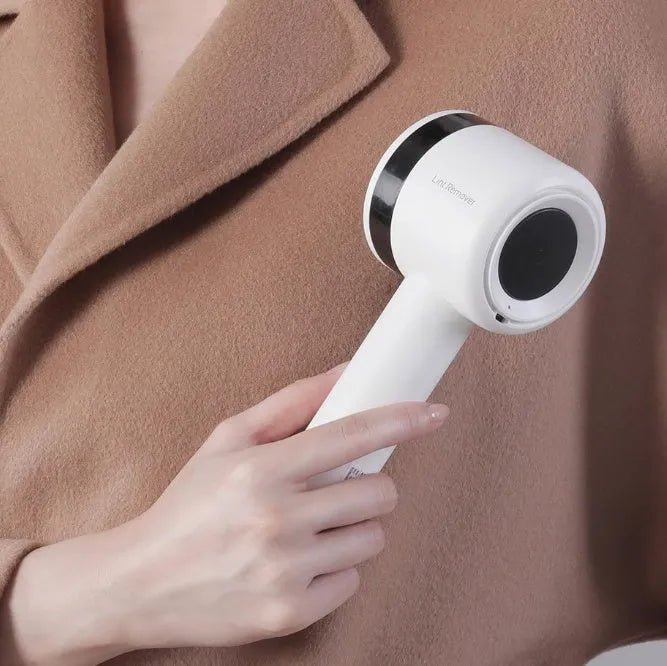 White rechargeable lint remover with hidden hair collection container and detachable three-blade head on white background