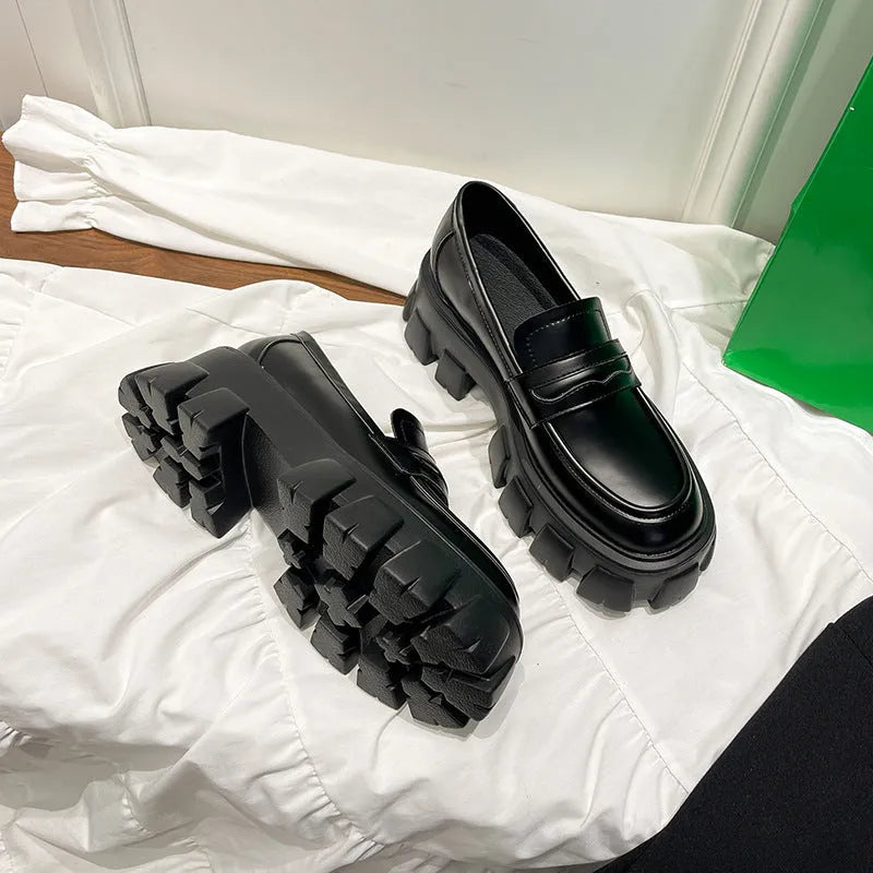 A pair of British style wide fit loafers in patent leather with a rubber sole.