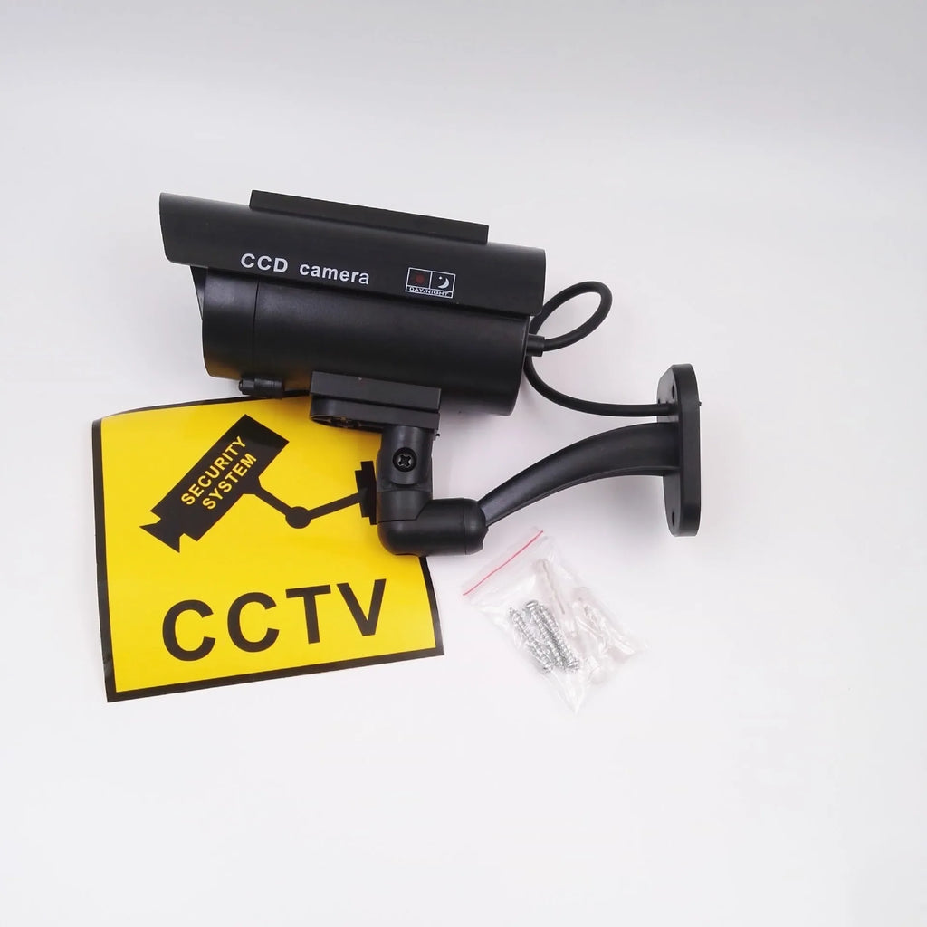 Black plastic solar-powered fake gun security camera with visible solar panel and spot light.