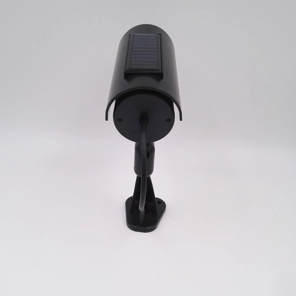 Black plastic solar-powered fake gun security camera with visible solar panel and spot light.