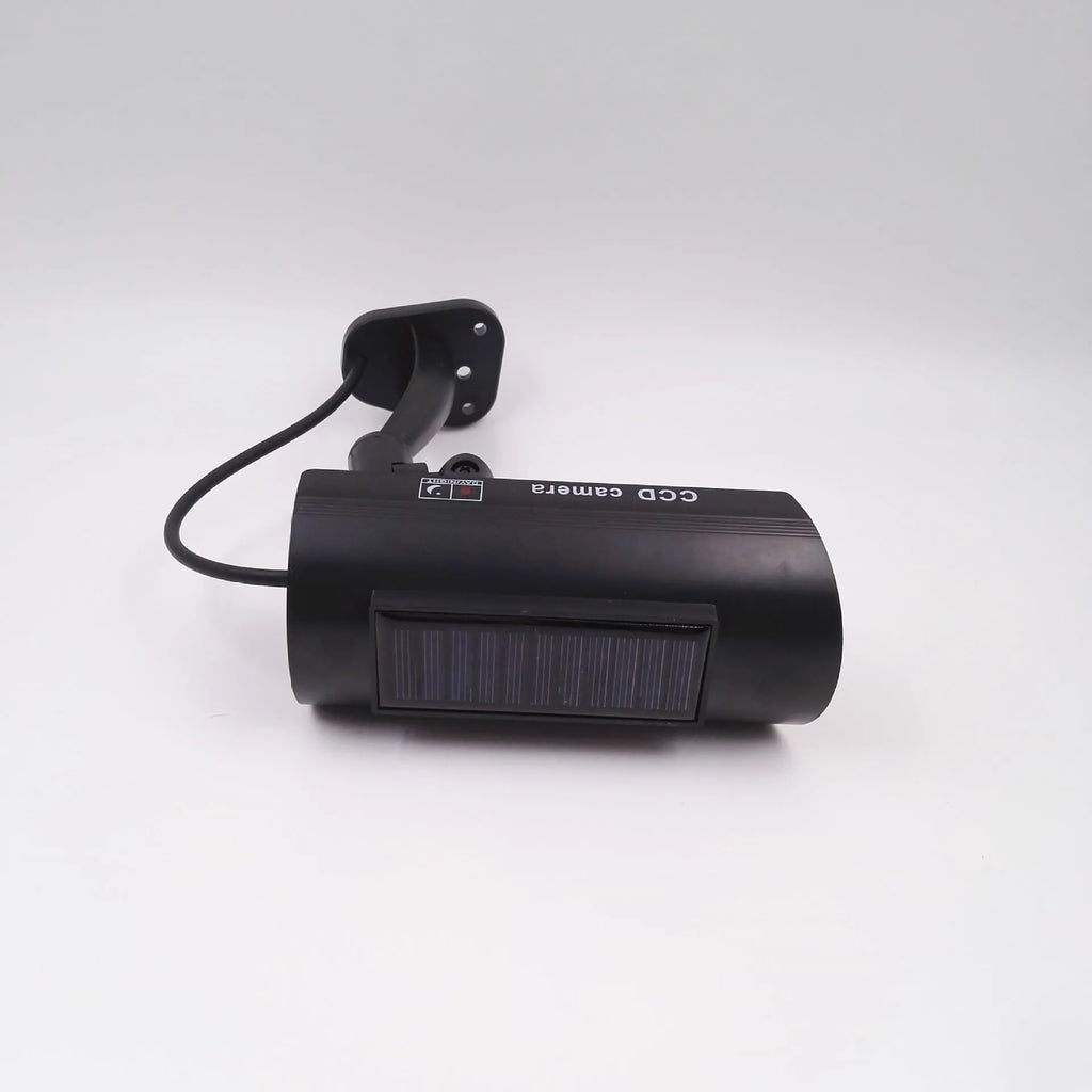 Black plastic solar-powered fake gun security camera with visible solar panel and spot light.