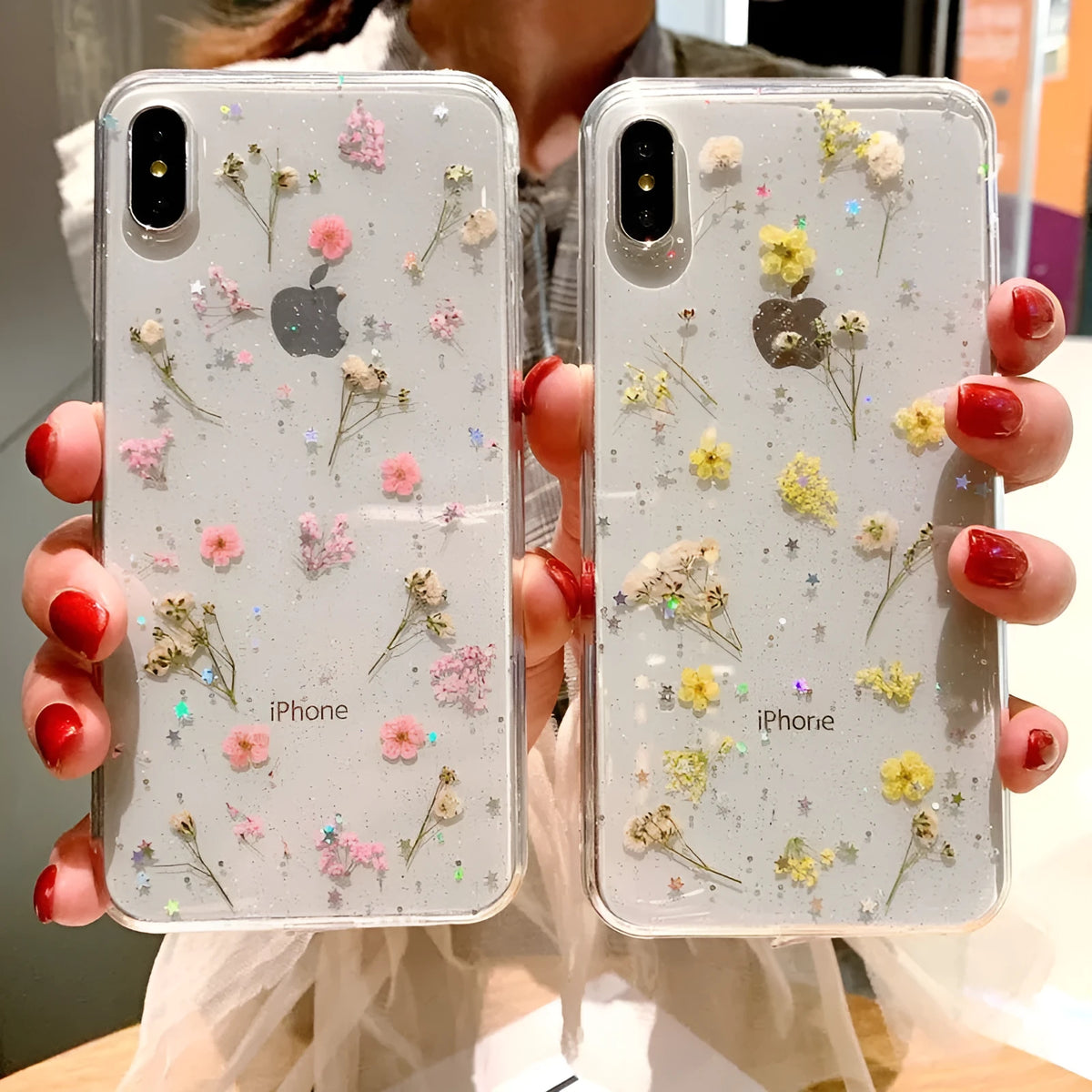 Clear TPU phone case with real dried pink flowers and glitter in epoxy, fitted on an iPhone