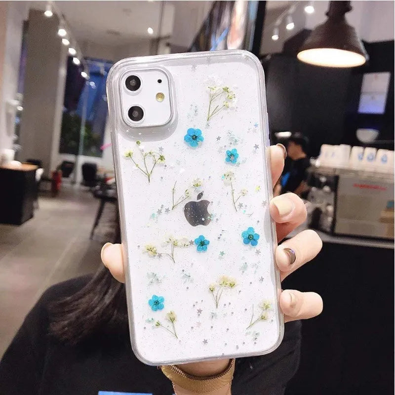 Clear TPU phone case with real dried pink flowers and glitter in epoxy, fitted on an iPhone