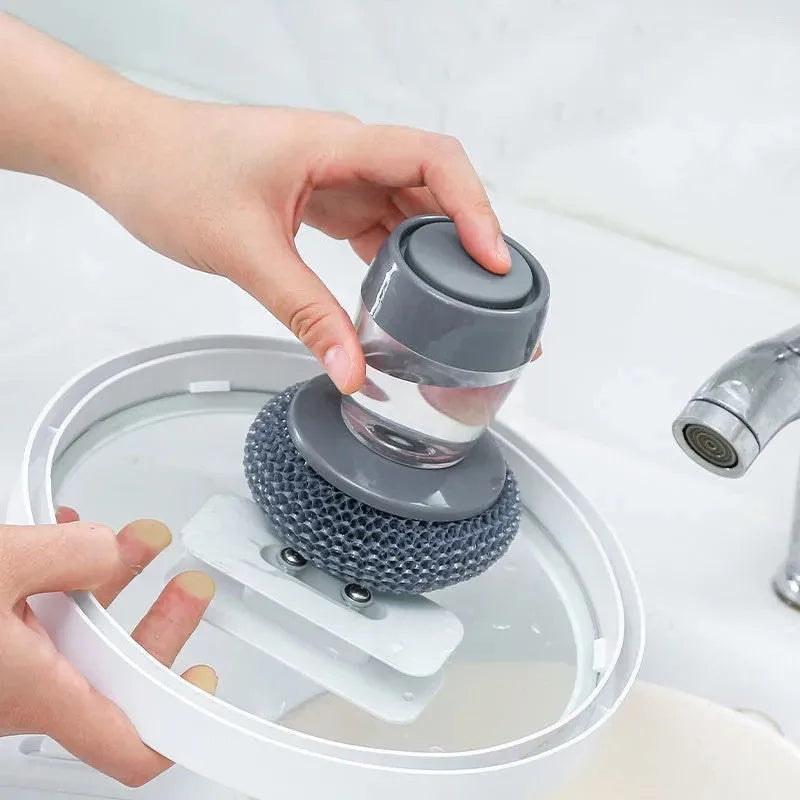 Push-type kitchen soap dispensing scrubber brush with PET construction on a kitchen counter.