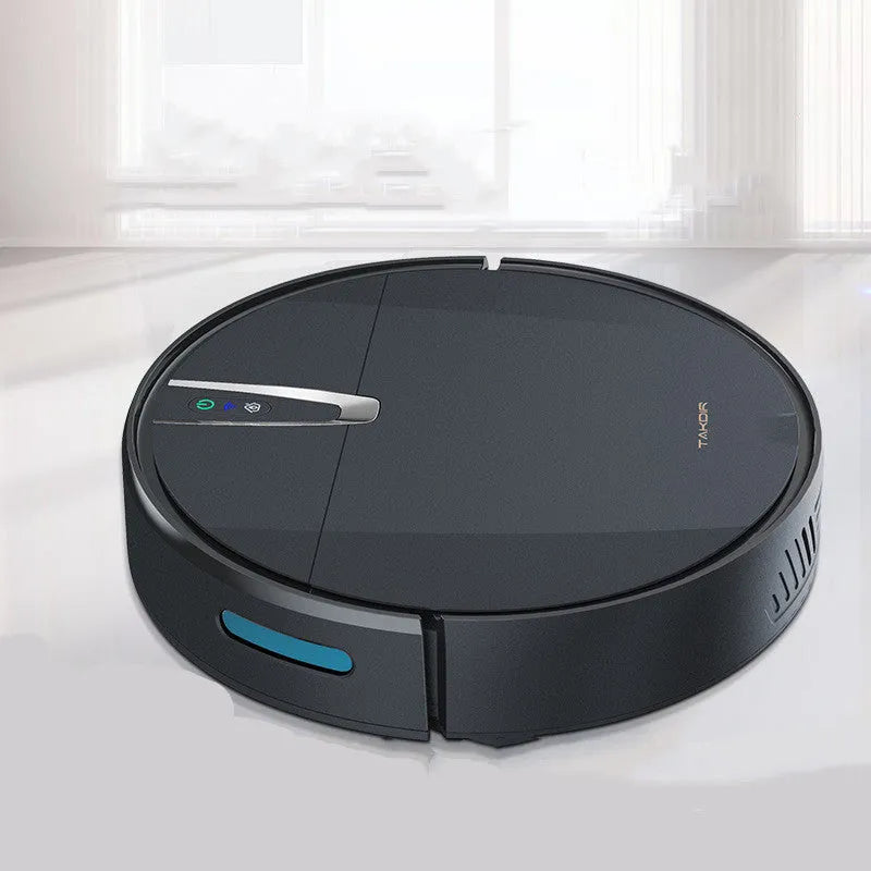 Black and white robotic floor cleaner with charging base, remote control, mop, and water tank on a hardwood floor.