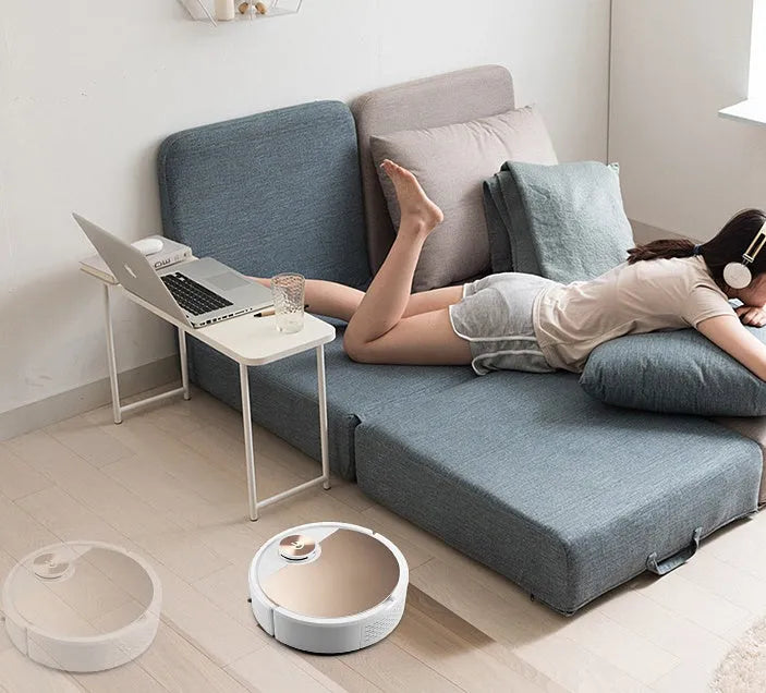 Golden coloured robotic vacuum cleaner with remote control on a hardwood floor.