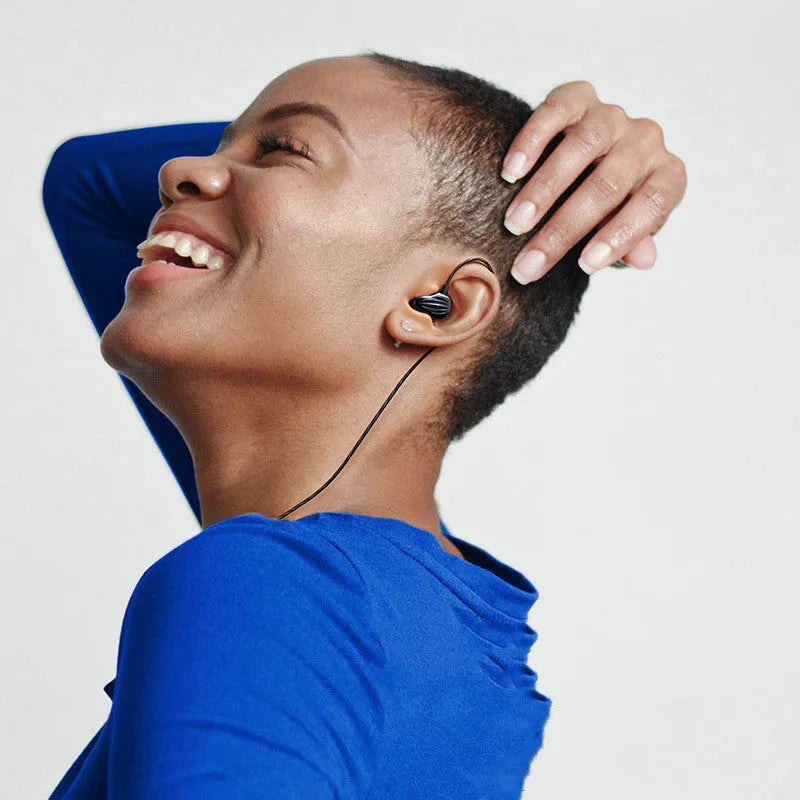 White in-ear sports headphones with black cable looped over the ear, showing the 3.5mm plug.