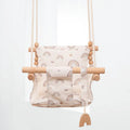 Cotton canvas baby swing chair with wooden seat and tassel decoration, hanging indoors.