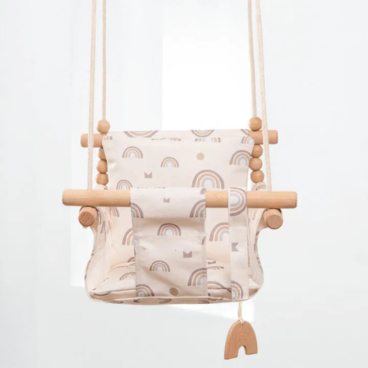 Cotton canvas baby swing chair with wooden seat and tassel decoration, hanging indoors.
