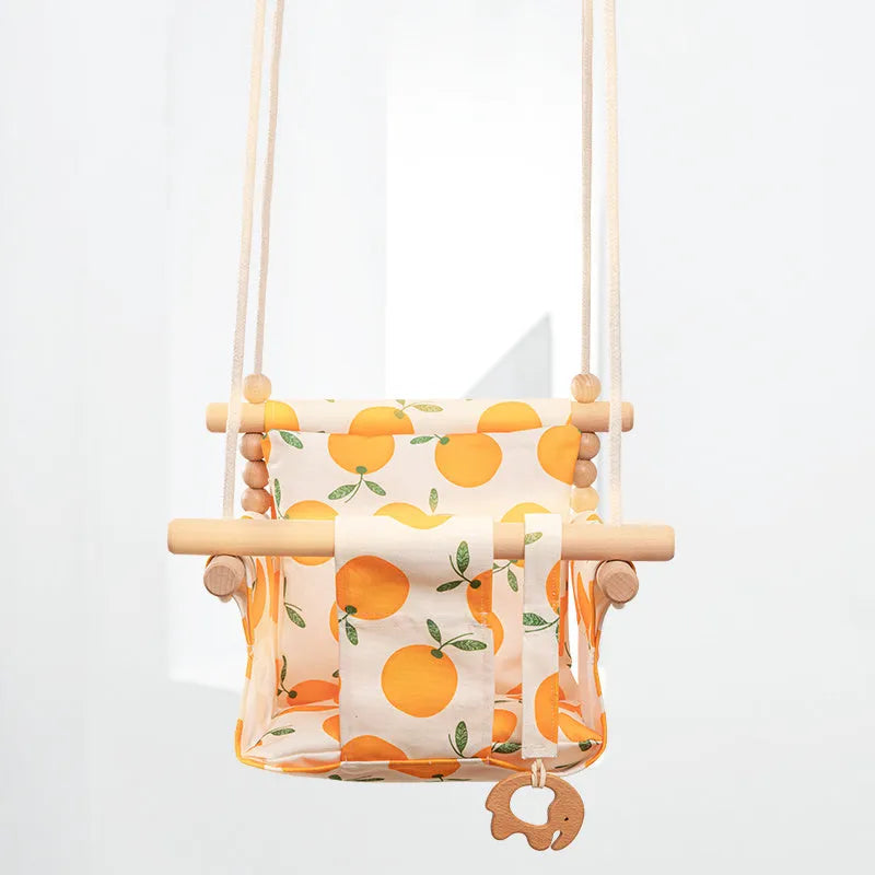 Cotton canvas baby swing chair with wooden seat and tassel decoration, hanging indoors.