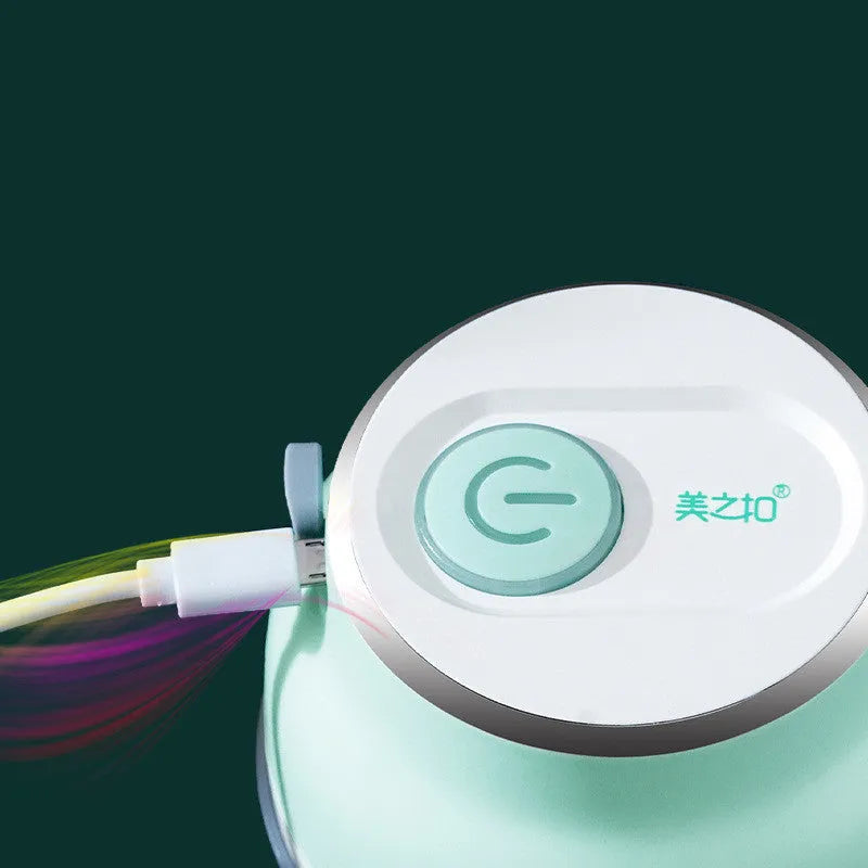 White portable electric mini food chopper with transparent cup and stainless steel blade on a kitchen counter.