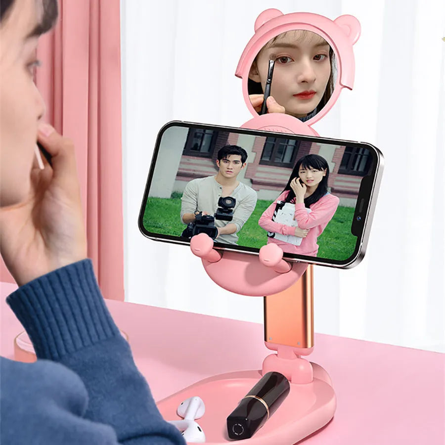 Blue foldable phone and tablet stand with a built-in mirror on a wooden desk.