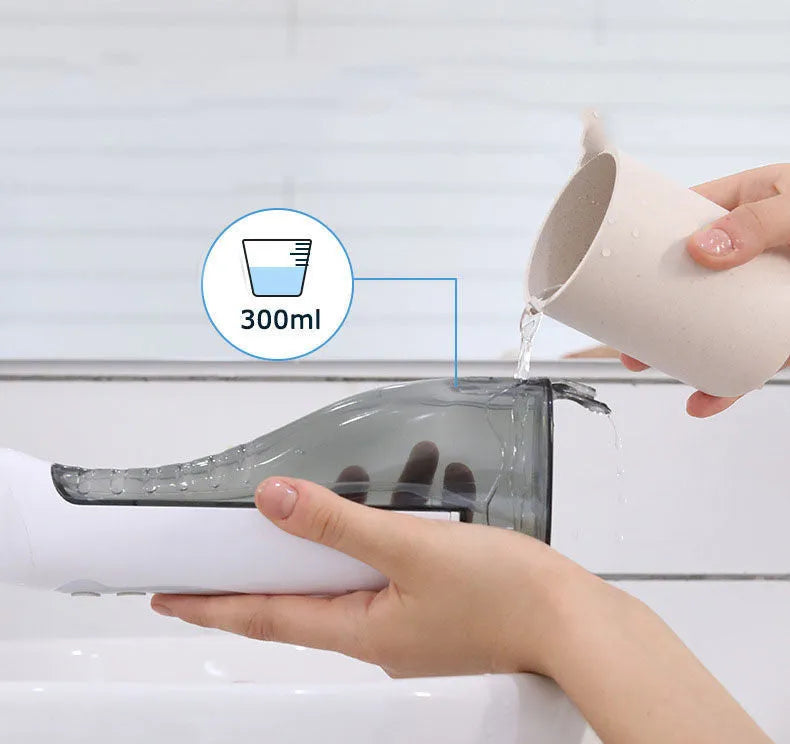 White portable oral irrigator water flosser with 330ml tank, 4 nozzles, and USB charging cable on a bathroom counter.