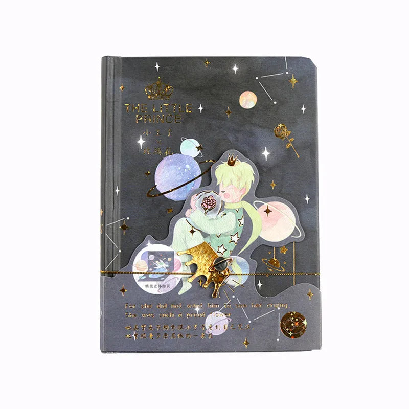 Hardback Little Prince notebook open on a table, showing one of four cover designs: sunset, bird, roses, or fox.