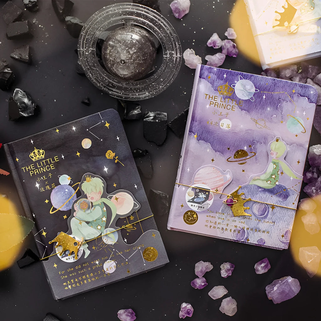Hardback Little Prince notebook open on a table, showing one of four cover designs: sunset, bird, roses, or fox.