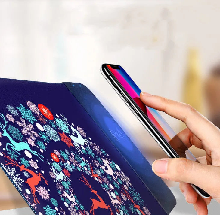 Black wireless charging mouse pad with RGB lighting and a cartoon design on a desk