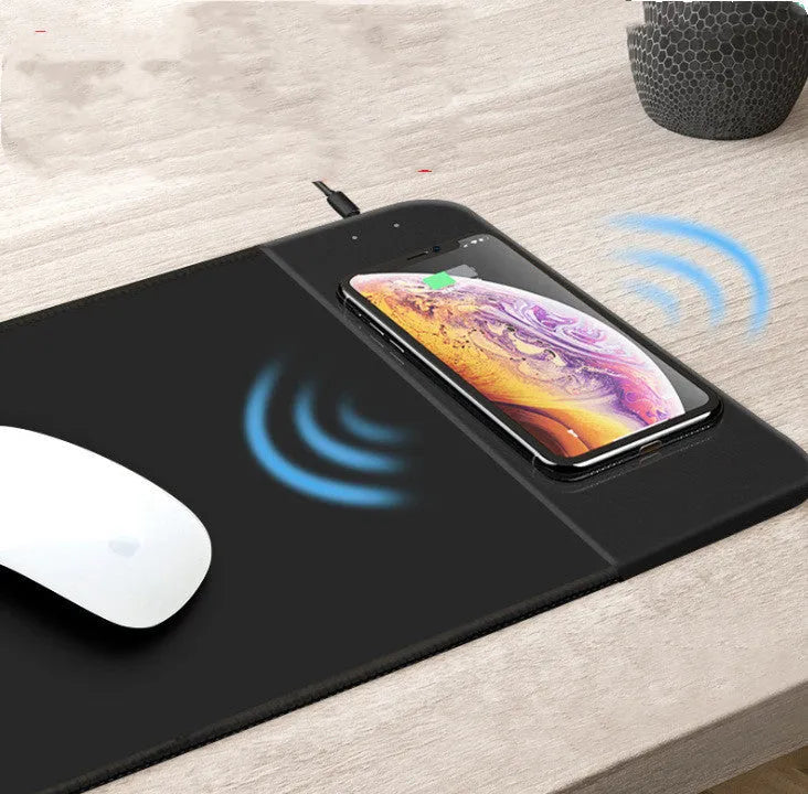 Black wireless charging mouse pad with RGB lighting and a cartoon design on a desk