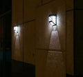Retro-style white solar wall light with solar panel and two LEDs, shown next to a mounting screw.