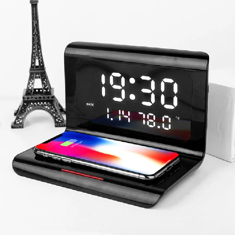 White wireless charger alarm clock showing digital time, date, temperature and humidity display on a desk.