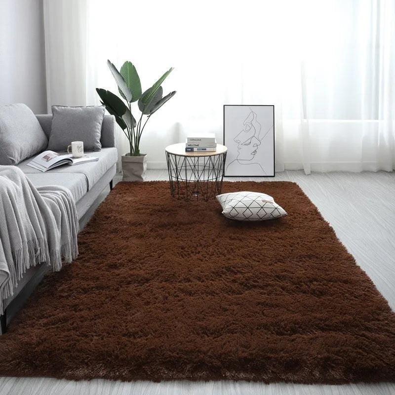Large rectangle fluffy plush carpet in a neutral colour on a wooden floor.