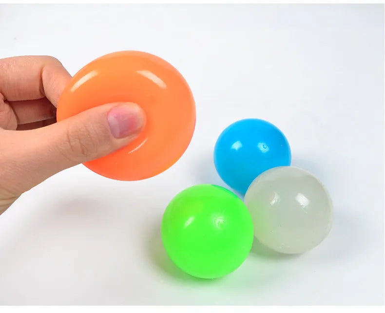 Luminous sticky ball toy in green colour glowing on a dark background, 4.5cm TPR squeeze ball for children