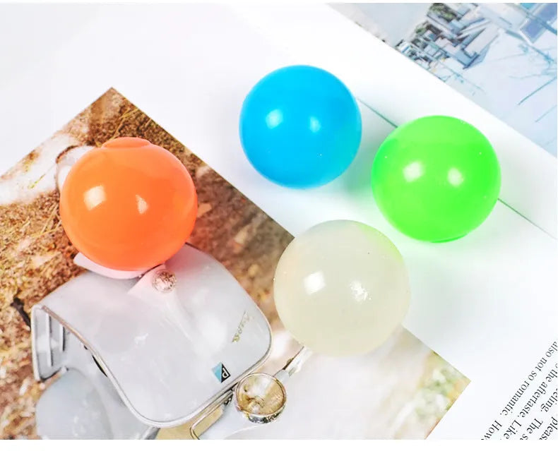 Luminous sticky ball toy in green colour glowing on a dark background, 4.5cm TPR squeeze ball for children