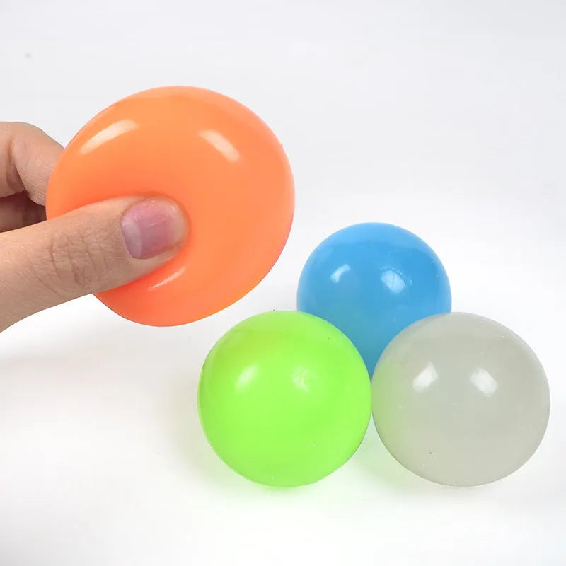 Luminous sticky ball toy in green colour glowing on a dark background, 4.5cm TPR squeeze ball for children