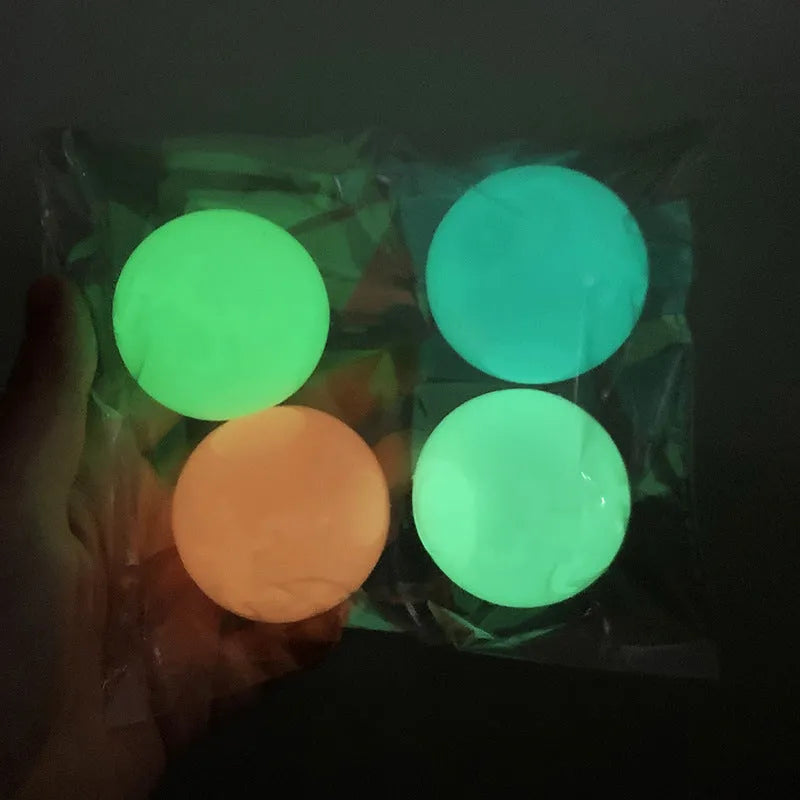 Luminous sticky ball toy in green colour glowing on a dark background, 4.5cm TPR squeeze ball for children